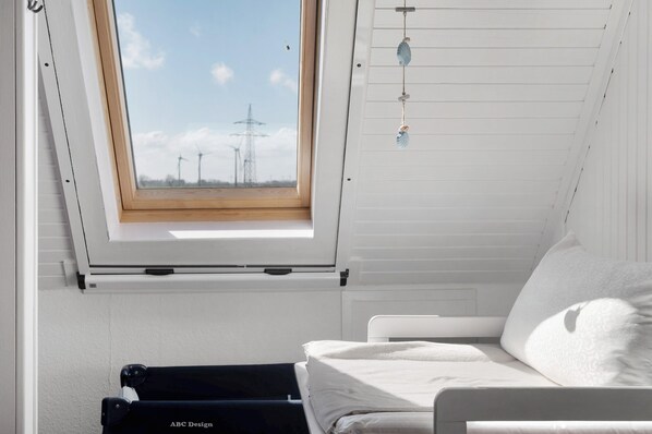 Una habitación con tragaluz, cama, un adorno colgante y vistas a aerogeneradores.
