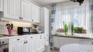 A kitchen with white cabinetry, a microwave, and a pink utensil holder.