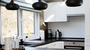 A modern kitchen with a central island, black chairs, and pendant lighting. - Tiny Home 'Seppl' with Mountain View, Wi-Fi, and Air Conditioning (Untergriesbach)