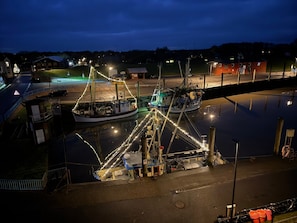 A marina with boats docked, a small building with a sign, and a pedestrian bridge.