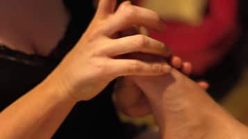 A close-up of a person's hands, one holding a small object, with a blurred background.