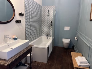 A bathroom with a sink, bathtub, toilet, and a bench with towels.