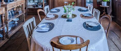 A dining room with a long table set for six, surrounded by wooden chairs.