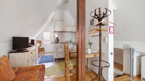 Ett mysigt vardagsrum med en tv, en soffa och en matplats med ett bord och stolar.