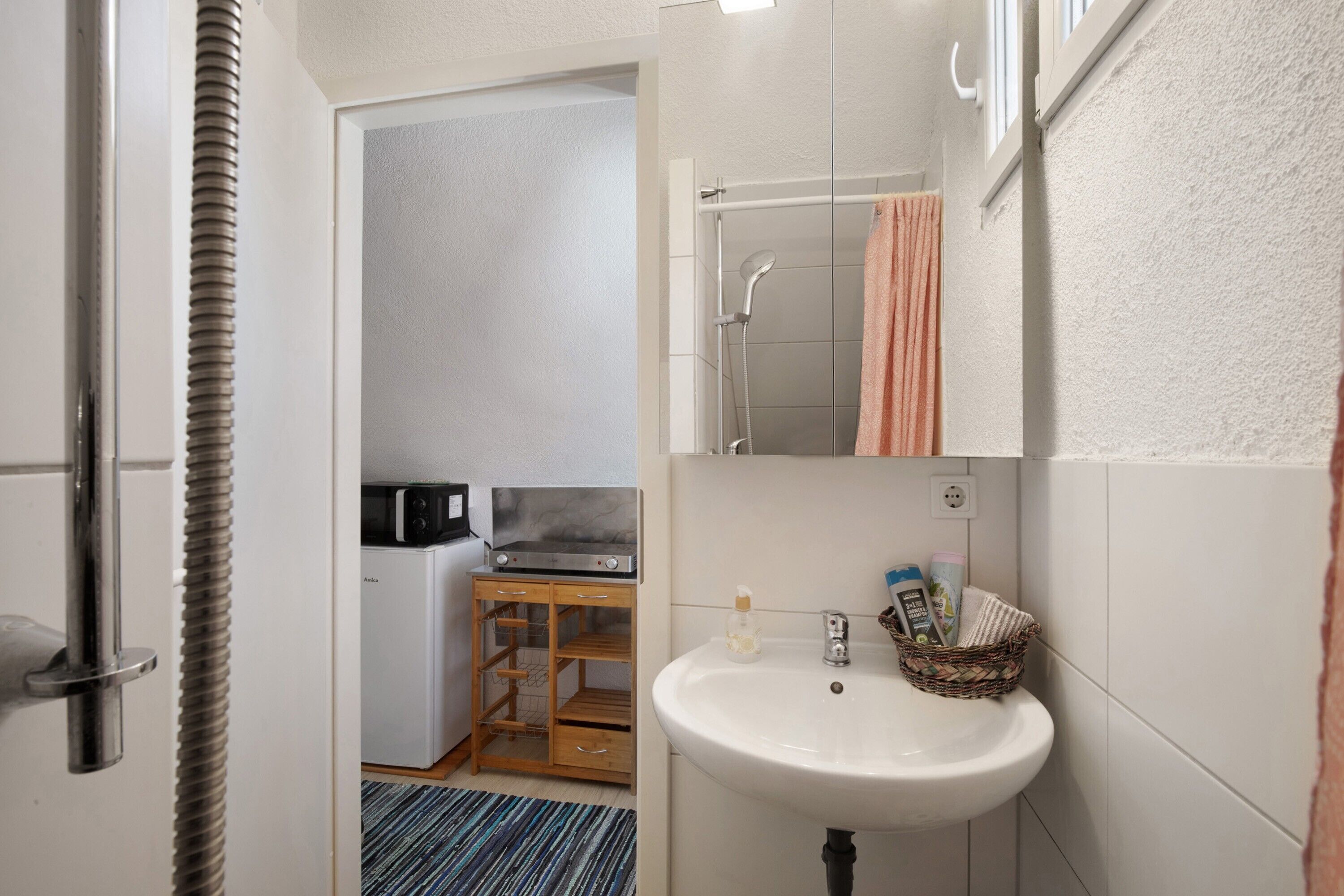 Un bagno con lavandino, specchio, porta asciugamani e doccia.
