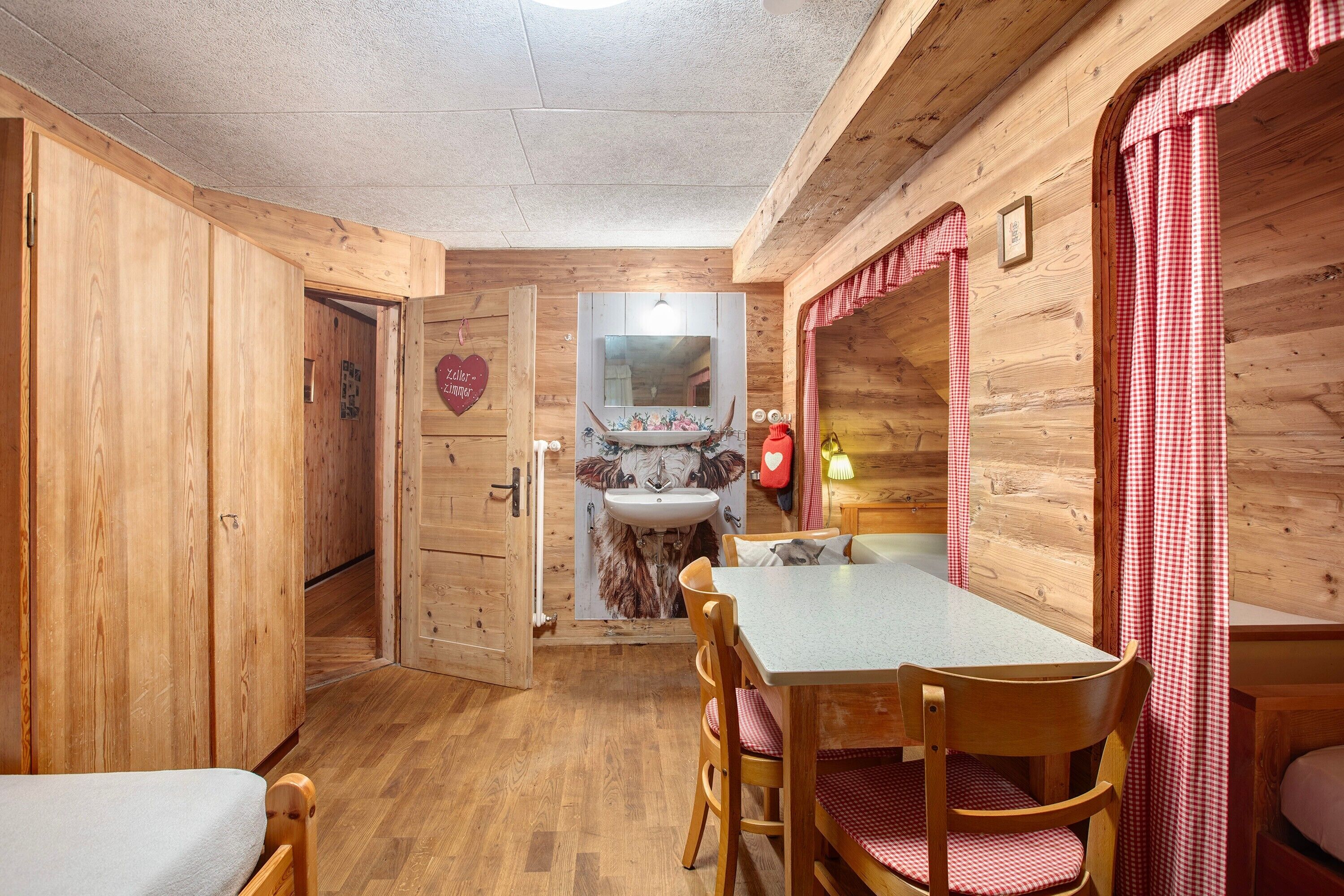 Un interno in legno con un tavolo da pranzo, sedie, un lavandino e uno specchio.
