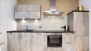 Una cocina moderna con armarios de madera, una campana extractora de acero inoxidable y un horno.