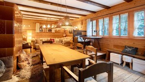 Interior rústico con una mesa de madera, bancos, un sofá y una guitarra.