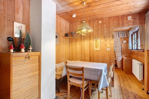 Un intérieur en bois comprenant une table à manger, des chaises, un luminaire suspendu et un radiateur.