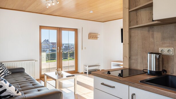 A modern kitchen with a wooden countertop, a kettle, and a view of the outside.