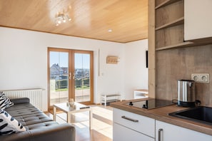 Cocina moderna con encimera de madera, una tetera y vistas al exterior.