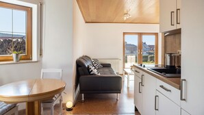 A modern kitchen with white cabinets, a black countertop, and a window overlooking a scenic view.