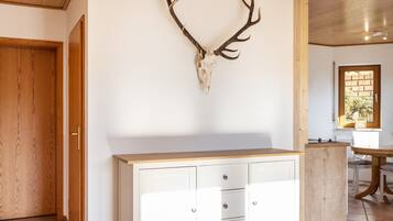 A room with a wooden door, a white cabinet, and a deer skull mounted on the wall.