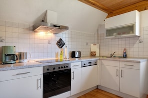 Uma cozinha com armários brancos, fogão de aço inoxidável, lava-louças e cafeteira.