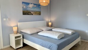 Ein Schlafzimmer mit einem Bett, zwei Nachttischen, einer Wandlampe und einem Gemälde.