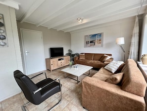 A living room with a sofa, coffee table, TV, and a lamp.