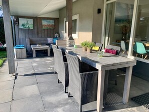 Eine Außenpatio mit Esstisch, Stühlen und einer Bank.