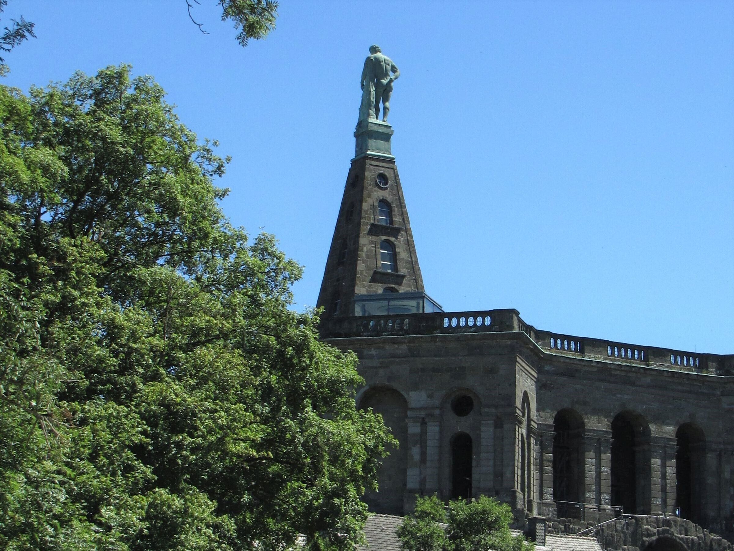 A building with a tall tower, a statue on top, and arched windows.