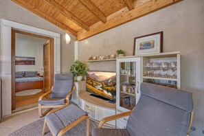 A cozy living room with a wooden ceiling, a television, a sofa, and a cabinet with glassware. - Apartment Jakara (Medulin)