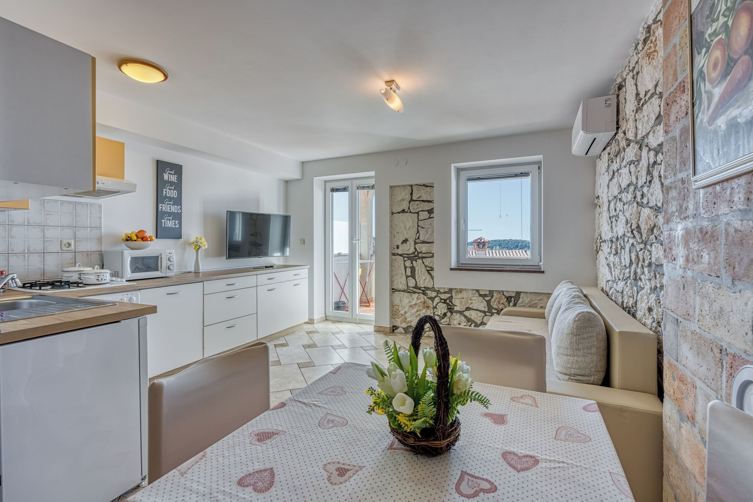 A modern kitchen with white cabinets, a built-in oven, and a dining area with a table set for two.