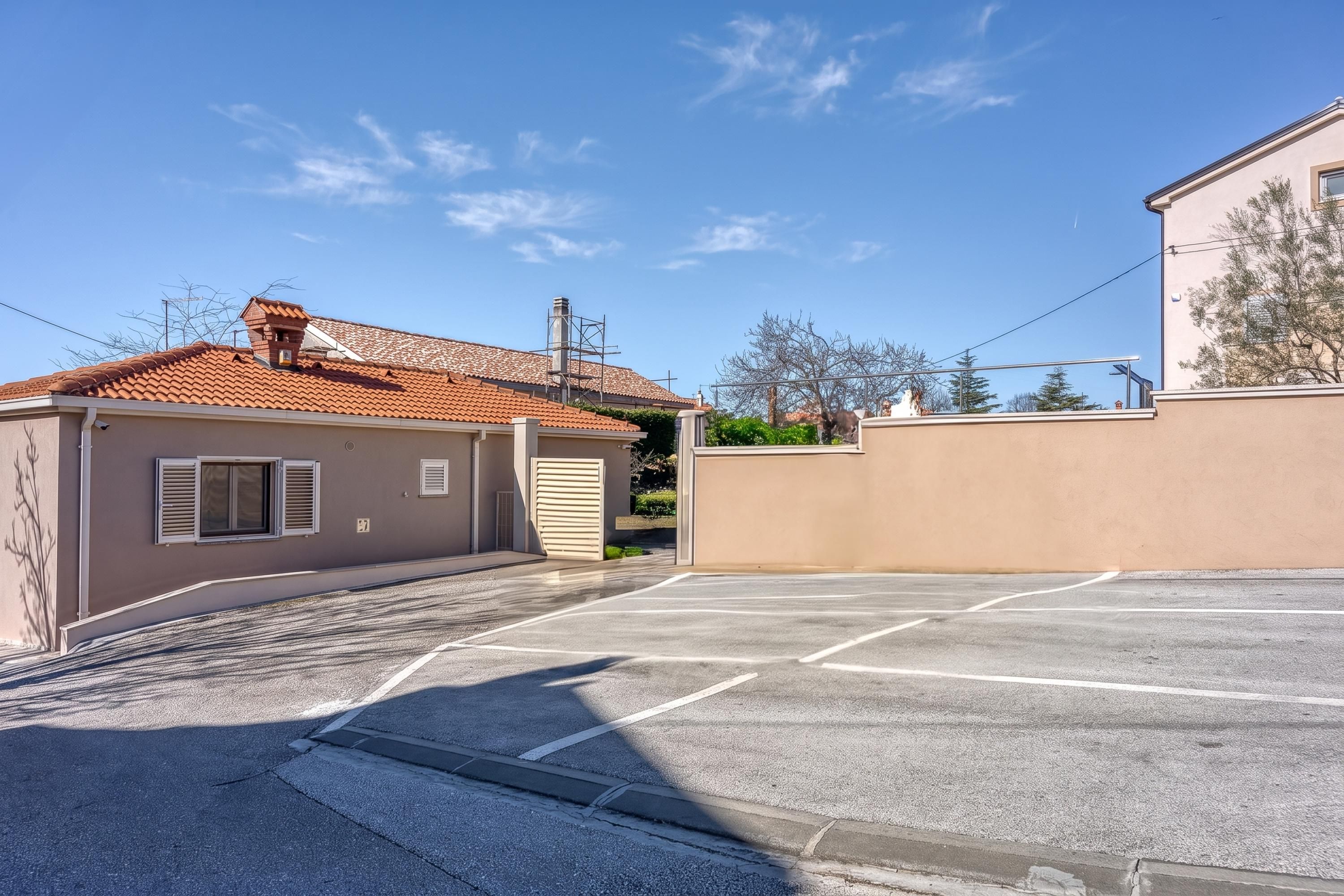 Un parking avec un bâtiment sur la gauche et un mur sur la droite.