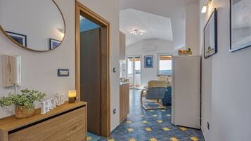 A hotel hallway with a wooden dresser, a mirror, and a bed in the background.