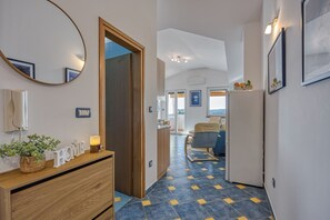 A hotel hallway with a wooden dresser, a mirror, and a bed in the background. - Apartment Jakara (Medulin)