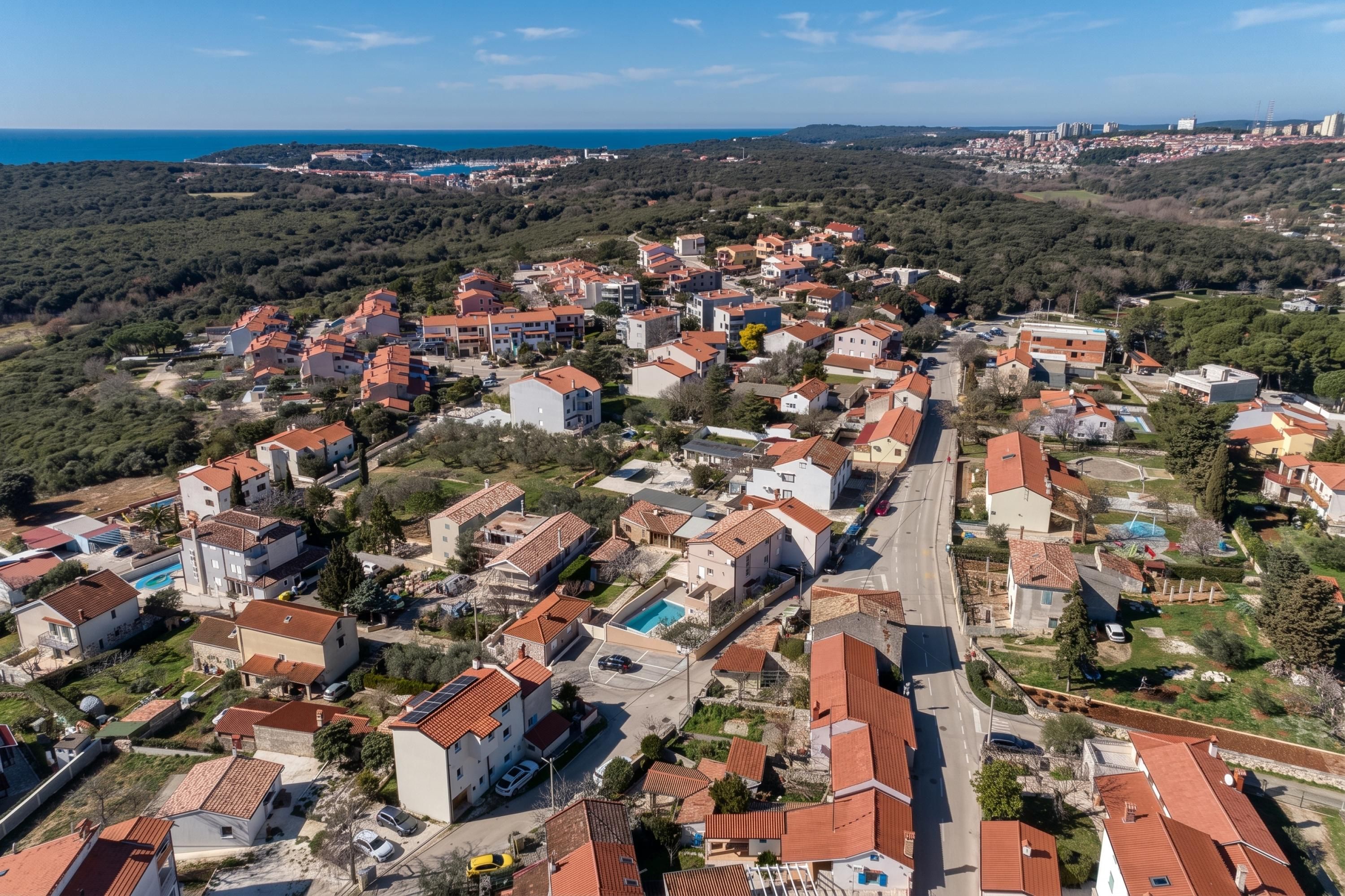 A residential area with houses, roads, and a body of water in the distance.