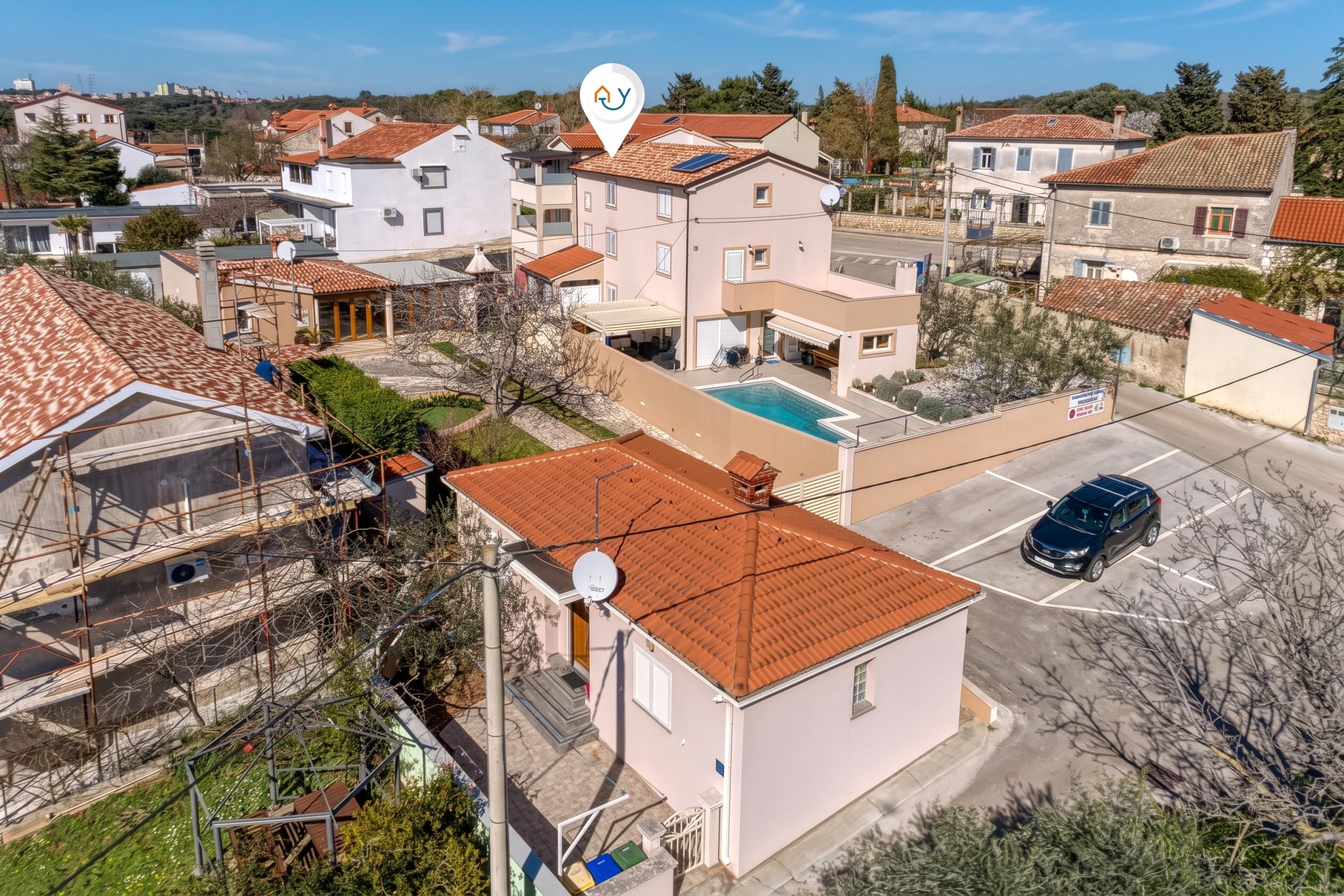 A residential area with houses, a swimming pool, and a parked car.