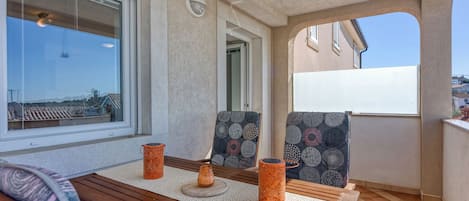 A balcony with a wooden table, two patterned chairs, and two orange vases.