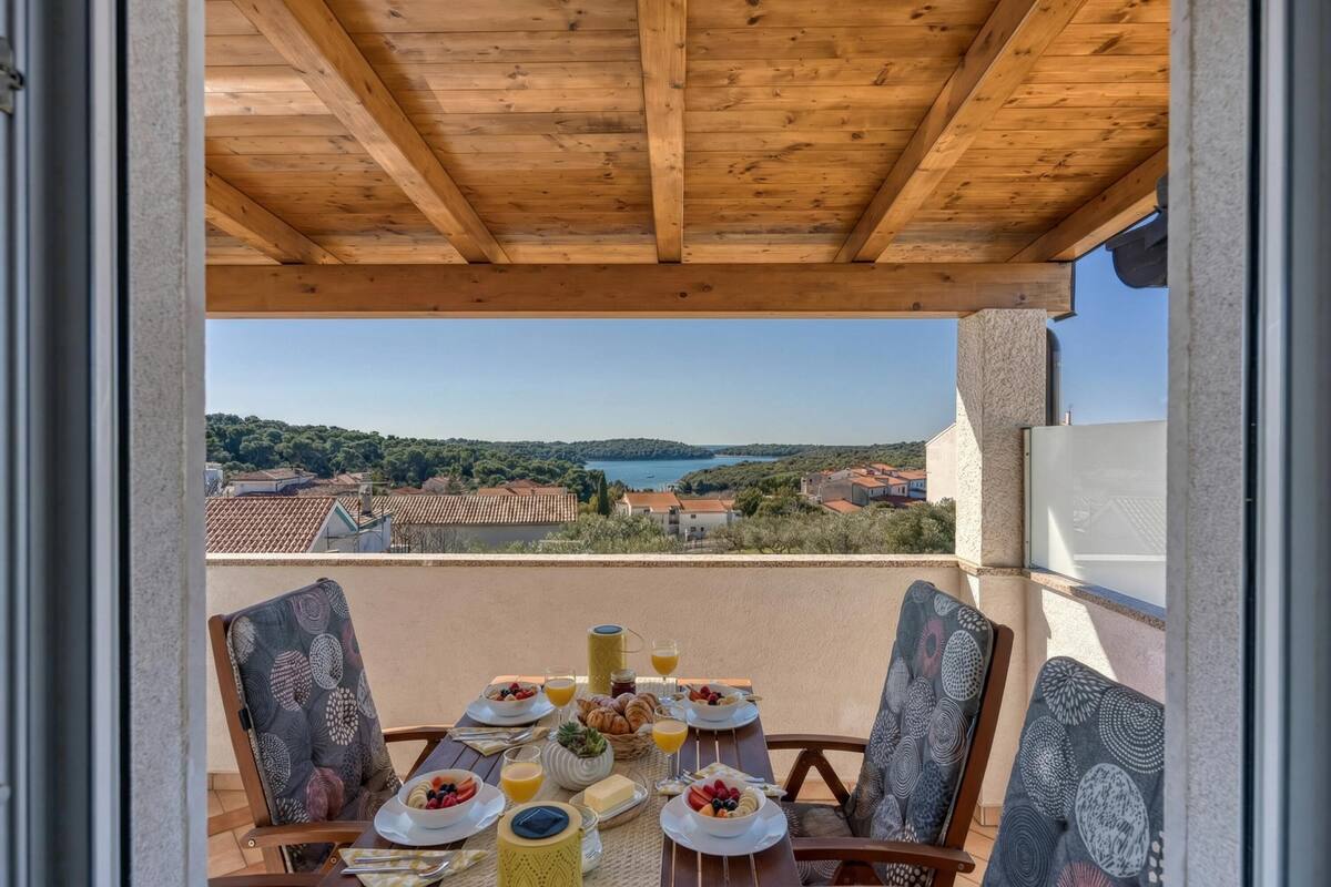 Un balcón con una mesa dispuesta para el desayuno, con vistas a un paisaje pintoresco.