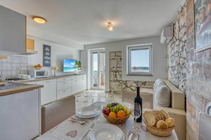 A modern kitchen with a dining area, stone wall, and a TV.