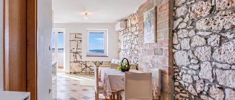 A dining area with a stone wall, a table with chairs, and a view through a window.