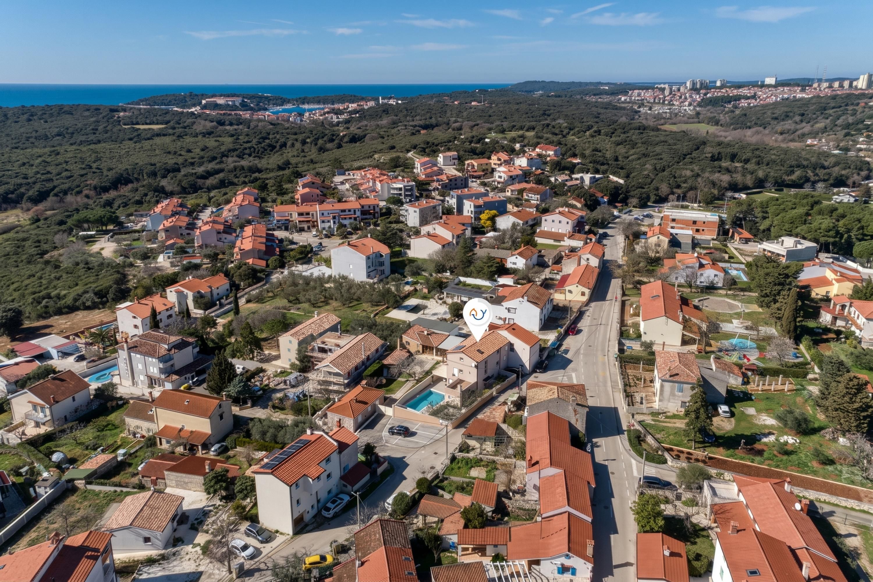 Ett bostadsområde med hus, vägar och en vattenyta i bakgrunden.