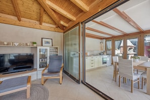 A modern interior with a TV, seating, kitchen, and sliding glass doors.