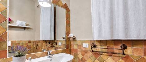 A bathroom with a white sink, a mirror, a towel rack, and a potted plant.