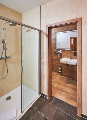 A modern bathroom with a glass-enclosed shower, a wooden vanity with a sink, and a mirror above the vanity. - Hotel 53 Nord (Brake)