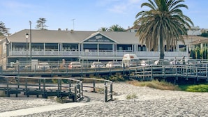 Ein Strandhotel mit Balkon, einer Palme und einem Strand im Vordergrund.