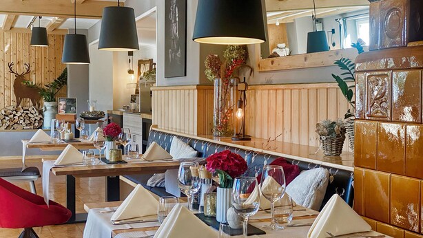 Un restaurante con paneles de madera, lámparas colgantes y una zona de bar con taburetes y una barra alta.