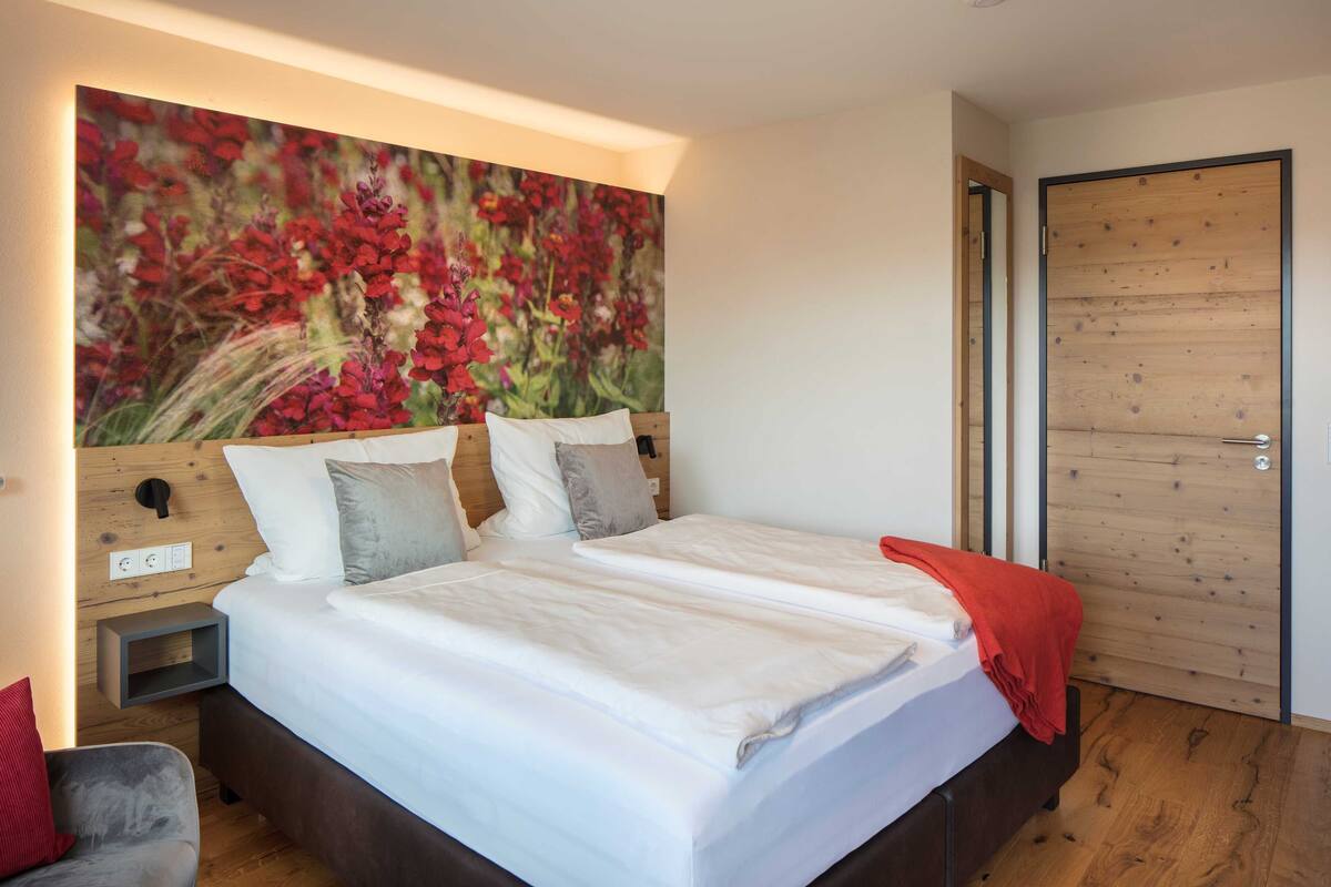 Un dormitorio moderno con una cama grande, cabecera de madera y un vibrante cuadro de flores.