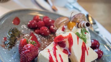Un plato de postre con fresas, frambuesas y gajos de grosella roja sobre una vajilla de cerámica.