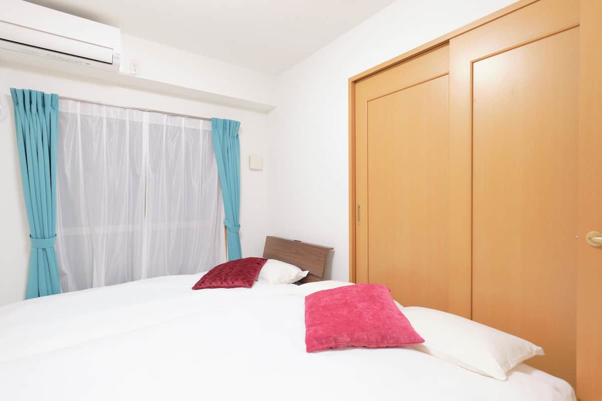 Ett hotellrum med en säng, gardiner, en luftkonditioneringsanläggning och en dörr av trä.