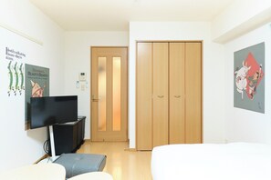Una habitación con televisor, sofá, armario de madera y obras de arte en las paredes.