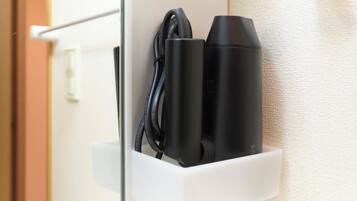 A white wall-mounted charging station with a black cable and two black cylindrical devices.