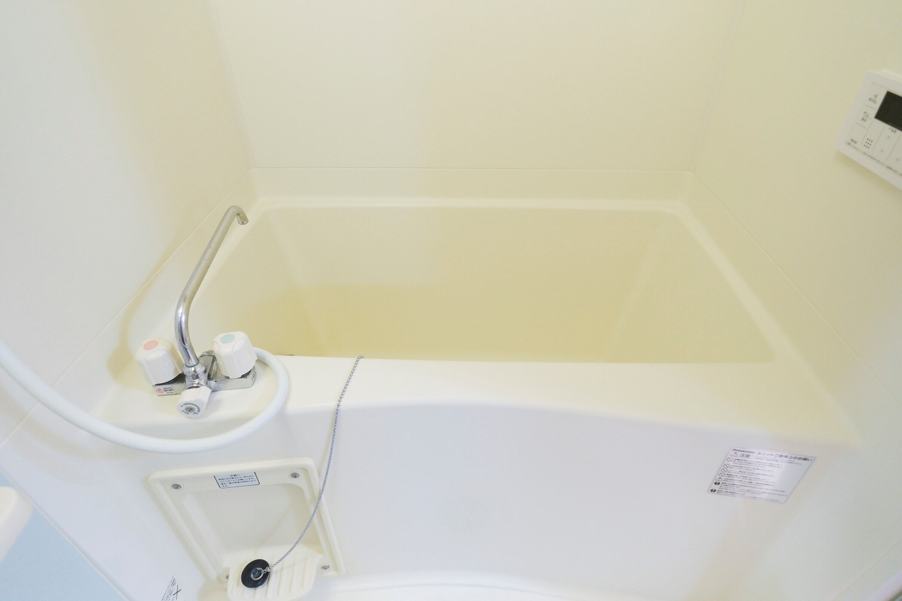 A bathtub with a faucet, a small sink, and a handrail.