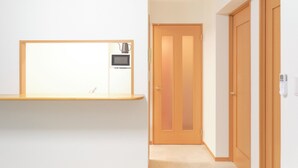 Un pasillo con estante empotrado, microondas y puerta con cerradura electrónica.