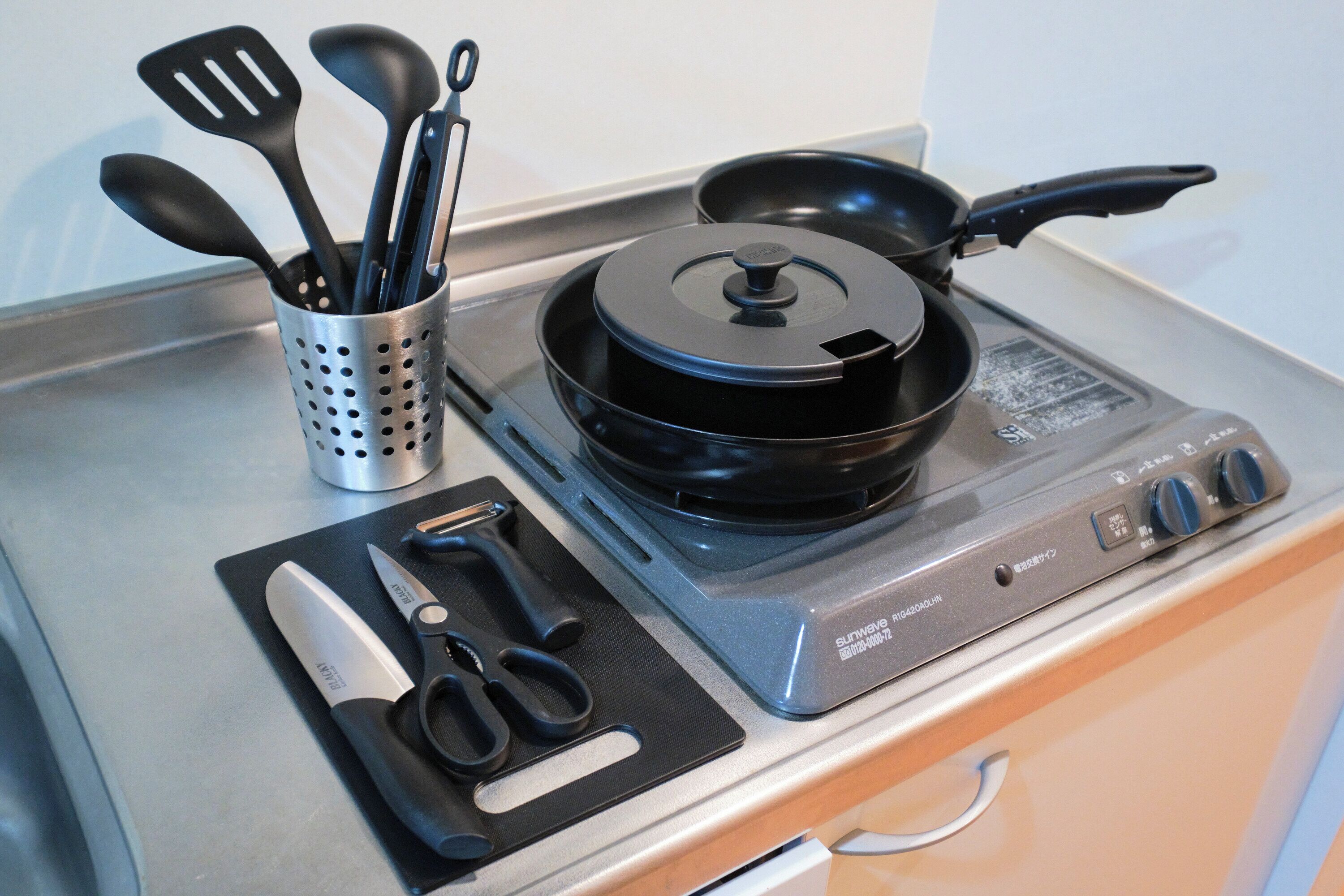 A kitchen with a stove, a frying pan, and various utensils.