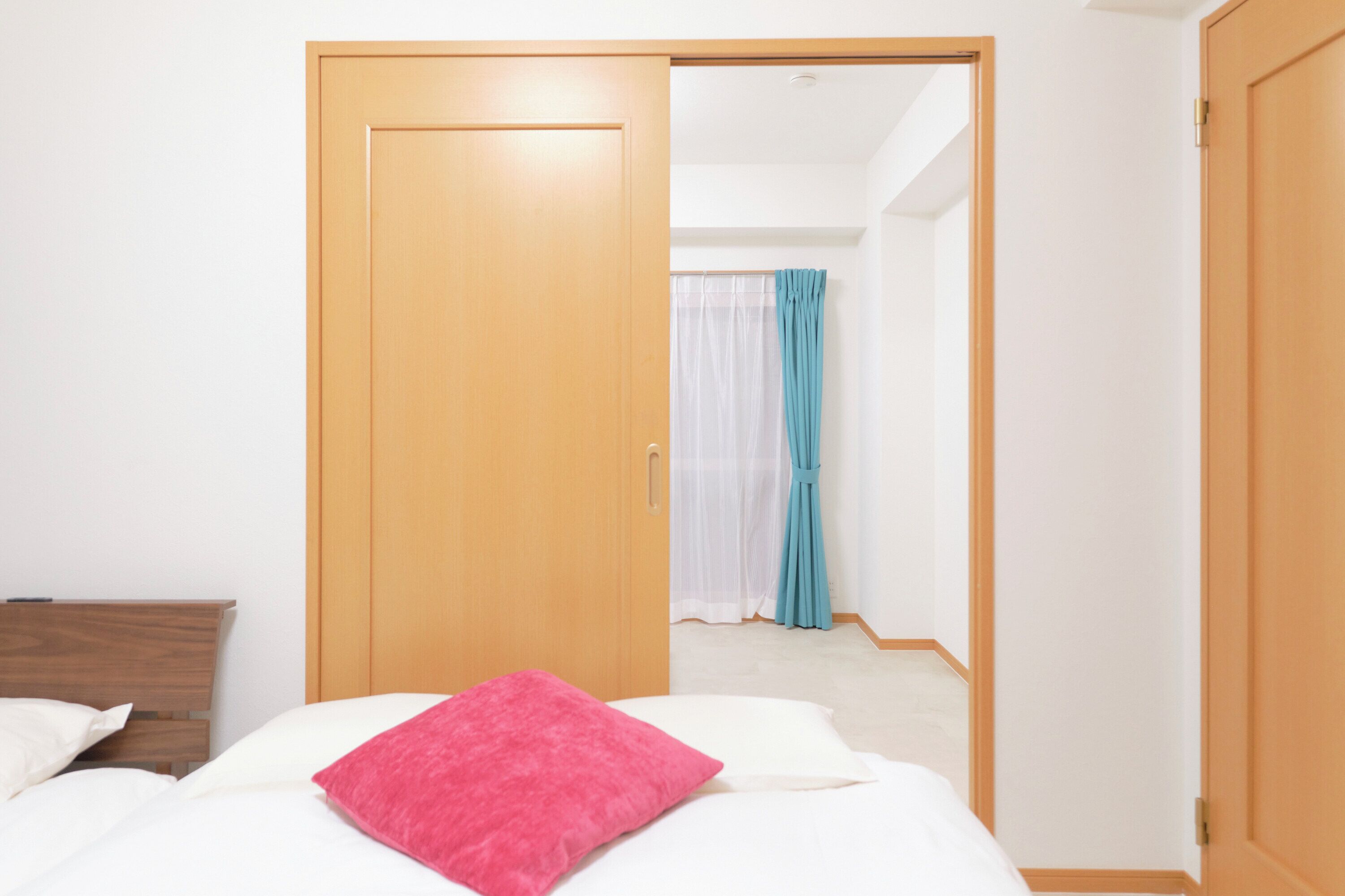 A hotel room with a bed, a wooden wardrobe, and a bathroom visible through an open door.