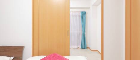 A hotel room with a bed, a wooden wardrobe, and a bathroom visible through an open door.