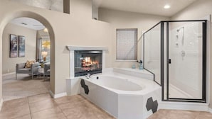 A modern bathroom with a freestanding bathtub, a glass shower enclosure, and a fireplace. - BNEW 6BR Postmodern 3k+sqft. Home in ABQ w/ Pool! (Albuquerque)